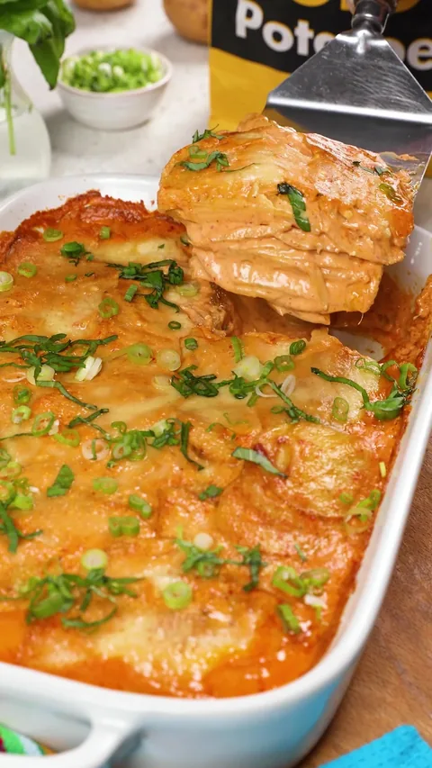 A spatula lifting a square out of the dish, showing the layers of potato and sauce.